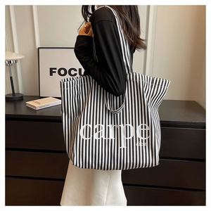Detailed side view of black and white striped canvas tote bag with Carpe Diem print