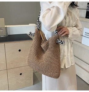 Detail of hand-woven straw tote bag with unique black and white striped knotted handle