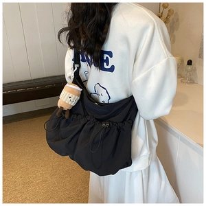 Detail of black nylon crossbody bag with drawstring design and coffee cup plush charm