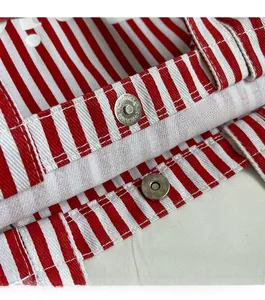 Macro detail of silver magnetic snap button on red and white striped canvas handbag