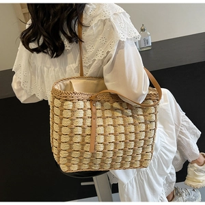 Texture détaillée d'un sac cabas en paille tissé main avec anses en cuir brun et doublure
