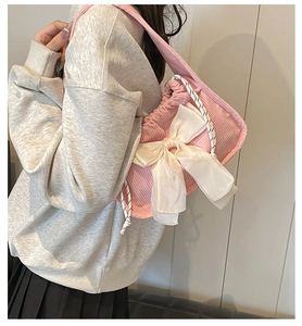 Pink corduroy shoulder bag with large white satin bow and woven handle detail