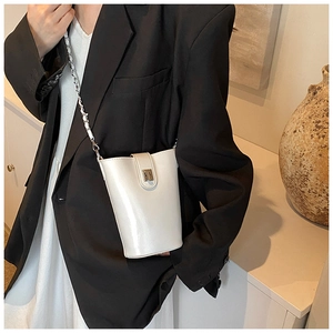 Dettaglio di una borsa a secchiello in pelle PU bianca con catena in metallo argentato