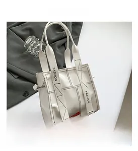 Details der weißen Lackledertasche mit schwarzen Kontrastnähten und modischem Gurt