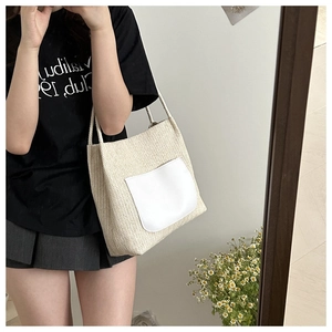 Détail du sac cabas en paille tissée avec poche en cuir blanc lors d'un selfie