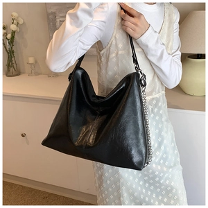 Close-up of a stylish black PU leather hobo bag with a decorative silver metal chain