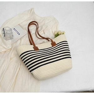 Minimalist woven straw tote bag with black stripes and brown leather handles for summer