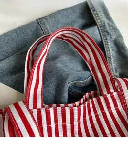 Close-up detail of reinforced red and white striped canvas bag handles with neat stitching
