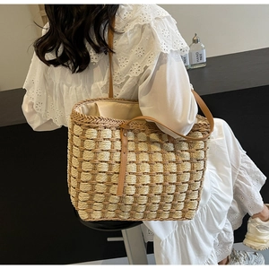 Détail du cabas en paille tressée avec motif à carreaux et anses en cuir marron