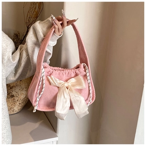 Detail of pink corduroy handbag featuring a large satin bow and drawstring closure