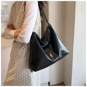 Detail of large black PU leather hobo bag with silver chain and thin shoulder strap