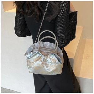 Detail of silver crossbody bag with gold tree pattern and sparkling rhinestone handles