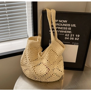 Sac fourre-tout beige en crochet avec motifs ajourés sur une table épurée