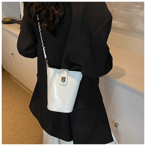 Elegante borsa a secchiello bianca con tracolla a catena e chiusura a girello su modella