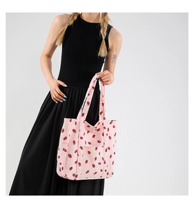 Detailed texture of pink corduroy tote bag with red strawberry print pattern