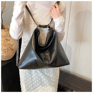 Detail of black glossy PU leather hobo bag showing triangular shape and shoulder strap