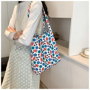 Detail of floral canvas tote bag featuring vibrant red and blue flower prints for women