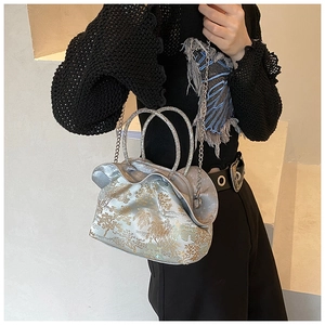 Detailed view of silver silk handbag with gold tree embroidery and crystal handles