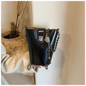 Dettaglio della borsa a secchiello in PU nero lucido con catena argentata e mini lucchetto decorativo