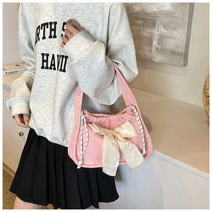 Detail of pink corduroy tote bag featuring a large white bow and striped drawstrings