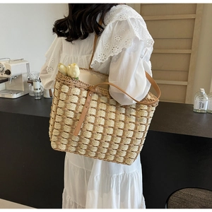 Détail d'un sac en paille tressée avec anses en cuir marron et doublure en lin beige