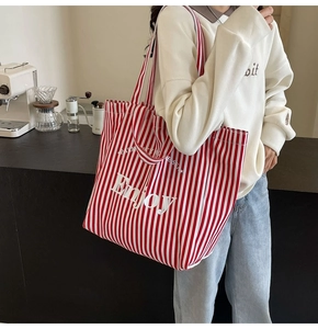 Red and white striped canvas tote bag with Enjoy text detail in a cafe setting
