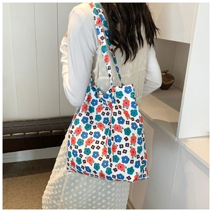 Floral canvas tote bag with abstract red and blue flowers shown on model's shoulder