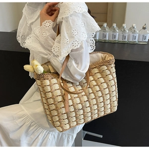 Détail du sac cabas en paille tissé à la main avec poignées en cuir marron et motif écossais