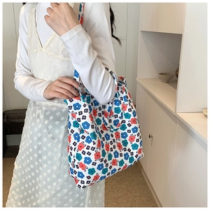 Close-up of cream canvas tote bag with vibrant red and blue floral print patterns