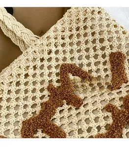 Detail of woven straw handbag texture featuring brown plush embroidery design