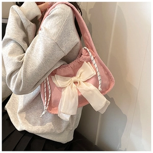 Detail of pink corduroy shoulder bag with large white chiffon bow and woven drawstrings