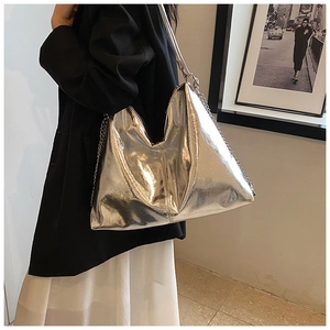 Detail of silver metallic tote bag with chain strap shown on a model's shoulder