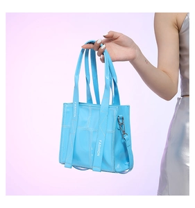 Detailansicht der hellblauen Lackleder-Handtasche mit weißen Nähten und Modegurt-Akzenten