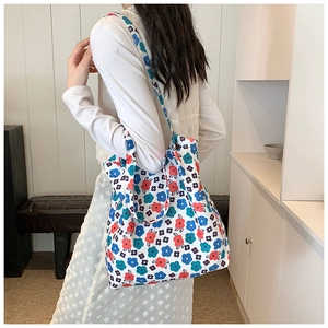 Detail of floral canvas tote bag with blue and red patterns worn by a model