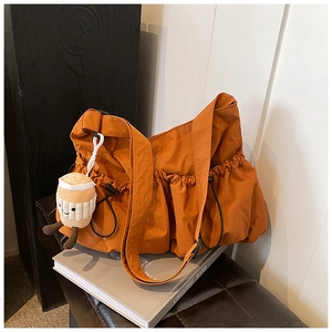 Minimalist caramel nylon crossbody bag with stylish ruched edges and latte plush pendant
