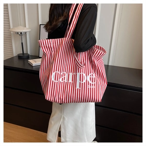 Detailed view of striped canvas tote bag with carpe diem text in a modern setting