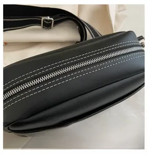 Detail of silver metal zipper and white contrast stitching on black PU leather bag