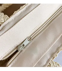 Close-up of smooth metal zipper and premium woven fabric on beige shoulder bag