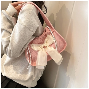 Pink corduroy shoulder bag featuring a large white chiffon bow and textured stripes