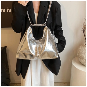 Silver metallic hobo shoulder bag with chain detail shown on model in a modern studio