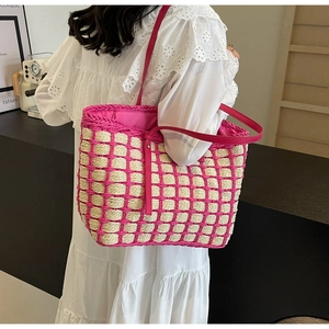 Détail d'un sac cabas en paille tissée à carreaux roses avec longues bandoulières élégantes