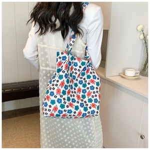 Detailed close-up of white canvas shoulder bag with colorful floral embroidery pattern
