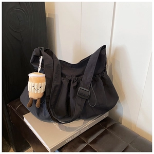 Minimalist black nylon crescent crossbody bag with ruffled design and plush coffee cup charm
