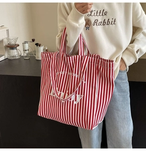 Detail of red and white striped canvas tote bag showing the dual handles and enjoy text