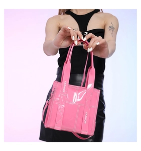 Detailaufnahme der pinkfarbenen Handtasche mit weißem Fashion-Schriftzug am Griff