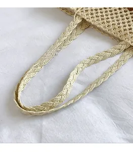 Detail view of thickened woven rope handles on a beige straw fabric handbag