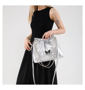 Detail of silver metallic pleated bag with butterfly clasp and crossbody chain strap