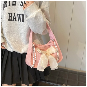 Detail of pink corduroy handbag featuring a large cream bow and drawstring closure