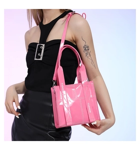 Detail der glänzend rosa Lackledertasche mit weißer Naht und Fashion-Schriftzug