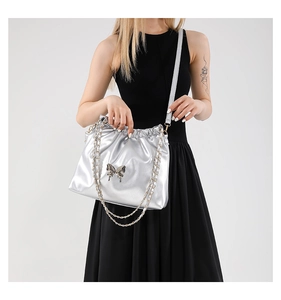 Detail view of shiny silver PU leather bag with metallic butterfly and chain strap
